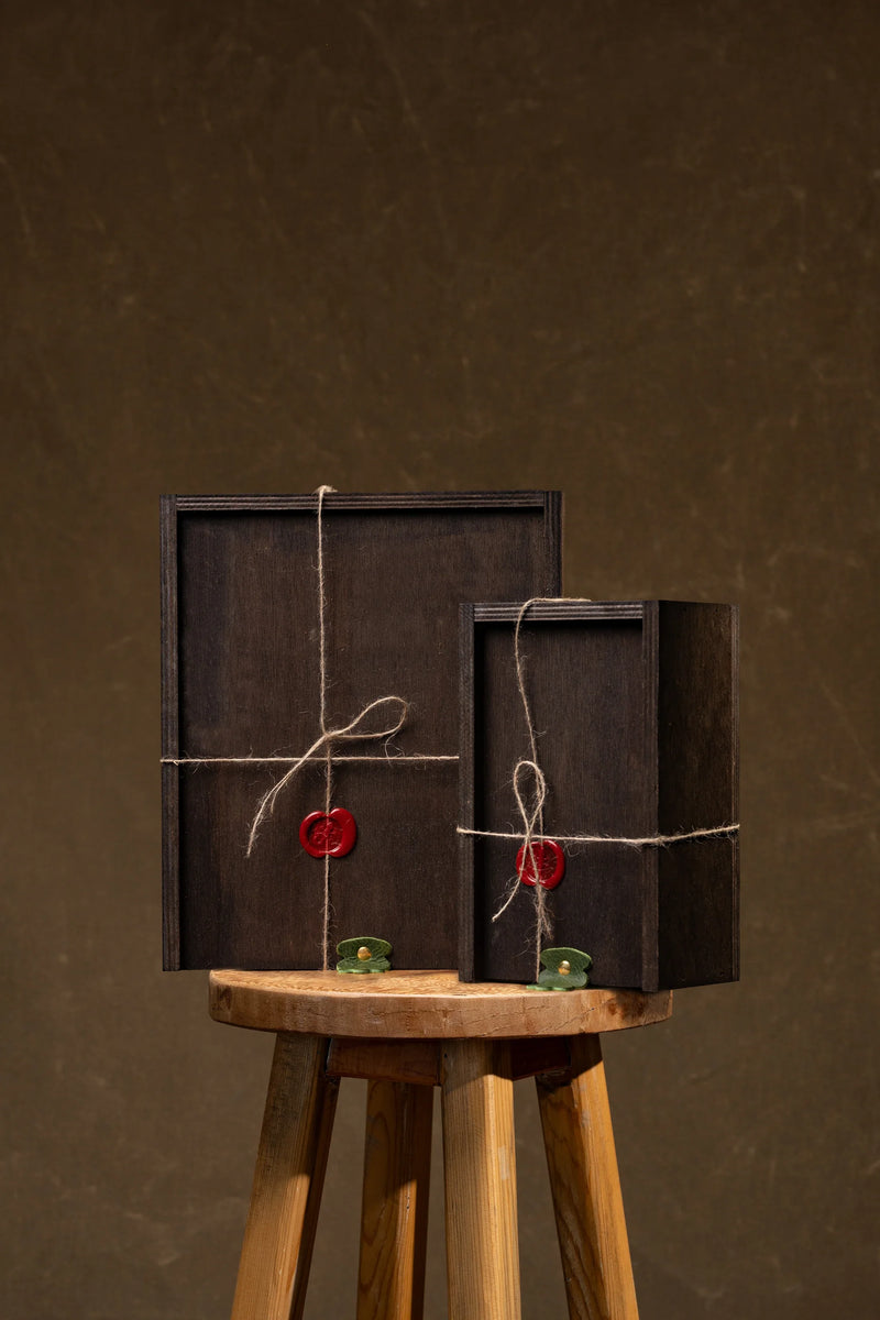 Two dark wooden gift boxes tied with twine and wax seals