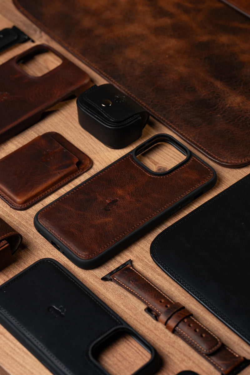 Leather phone cases, watch straps and a card wallet laid out flat