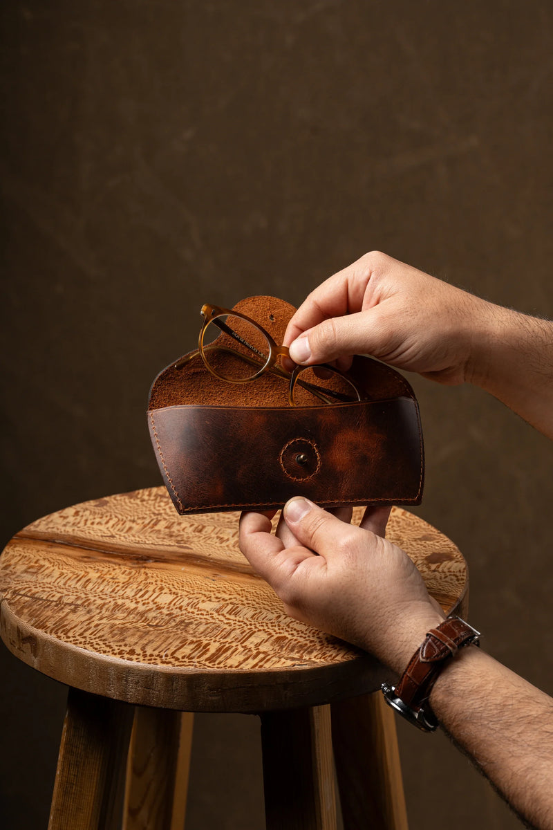 Hands opening a leather glasses case with eyeglasses inside