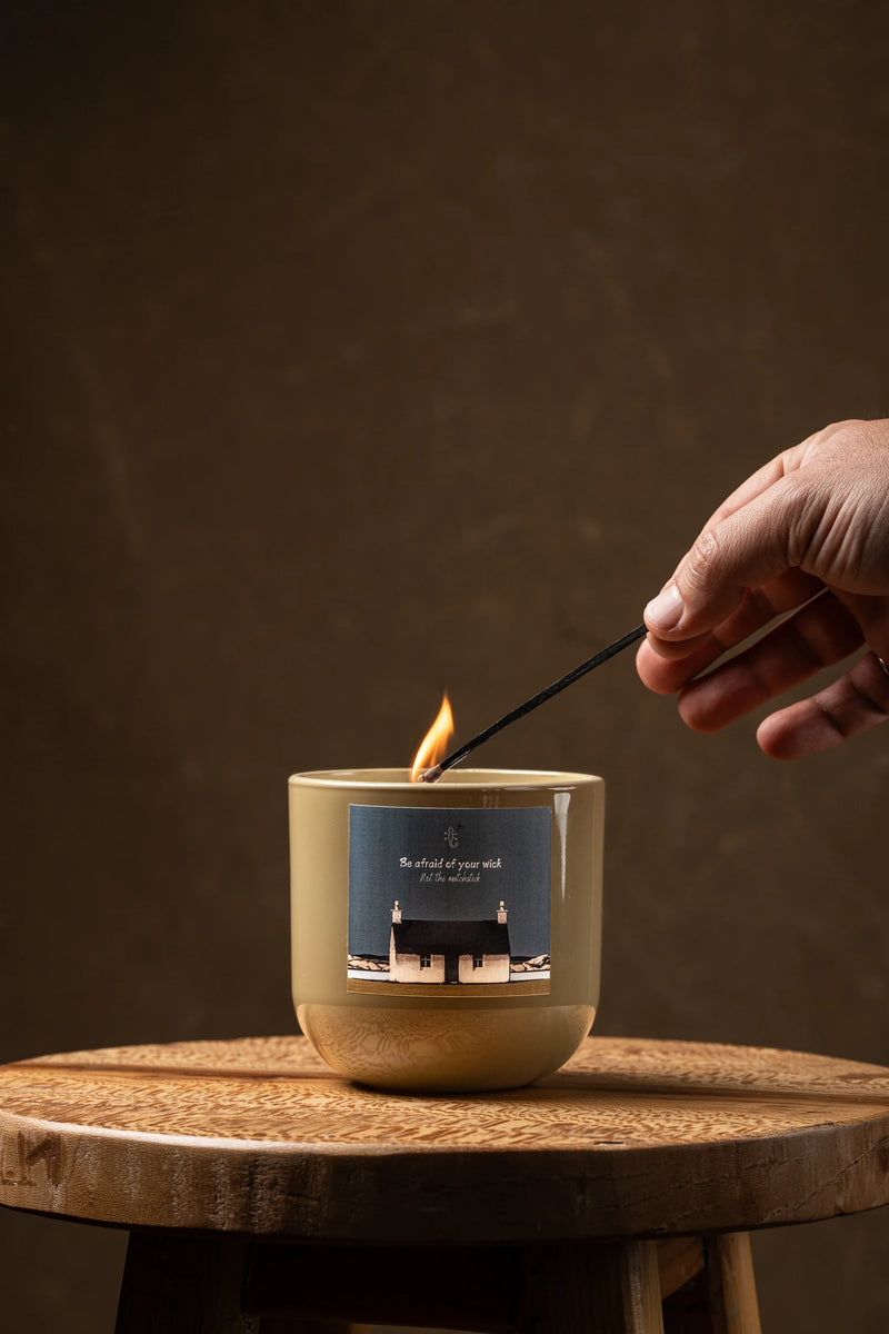 Hand lighting a scented soy candle in a ceramic vessel