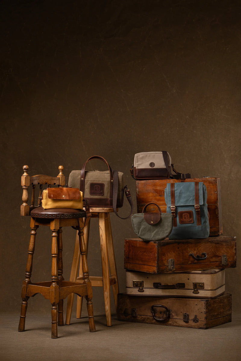 Canvas and leather bags displayed on stacked vintage suitcases